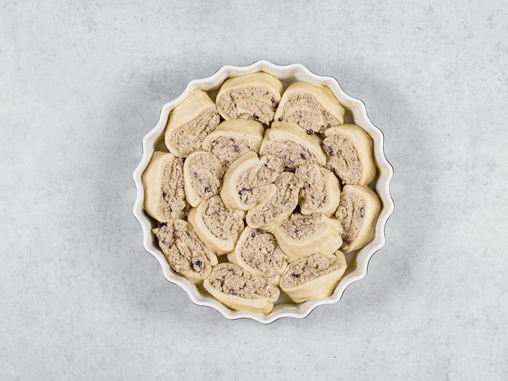 Ślimaczki drożdżowe z białym makiem ułożone obok siebie w formie do tarty