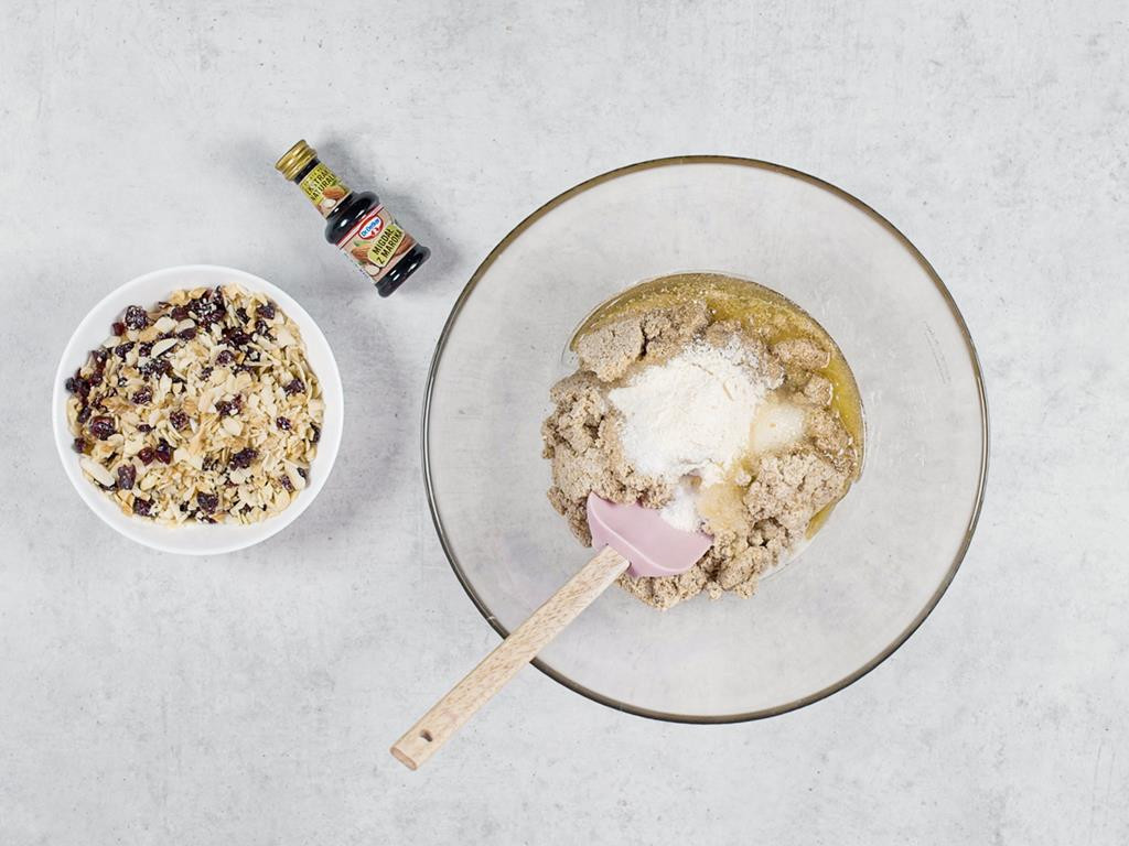 Mak wymieszany z miodem, cukrem i masłem w misce, posiekane bakalie w miseczce, ekstrakt migdałowy Dr. Oetker