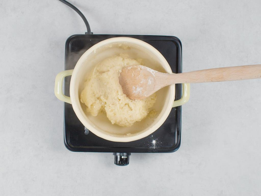 ciasto parzone na pączki w garnku z drewnianą łyżką