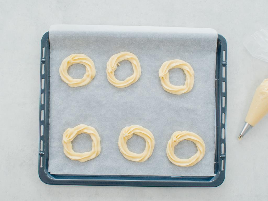 Ciasto przełożone do rękawa cukierniczego i wyłożone  na papier do pieczenia w kształcie 6 krążków
