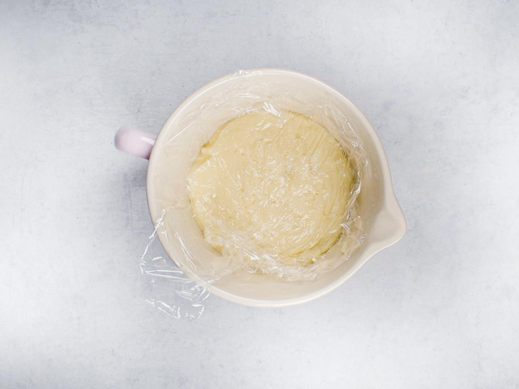 Przygotowany budyń z masłem w misce, przykryty folią