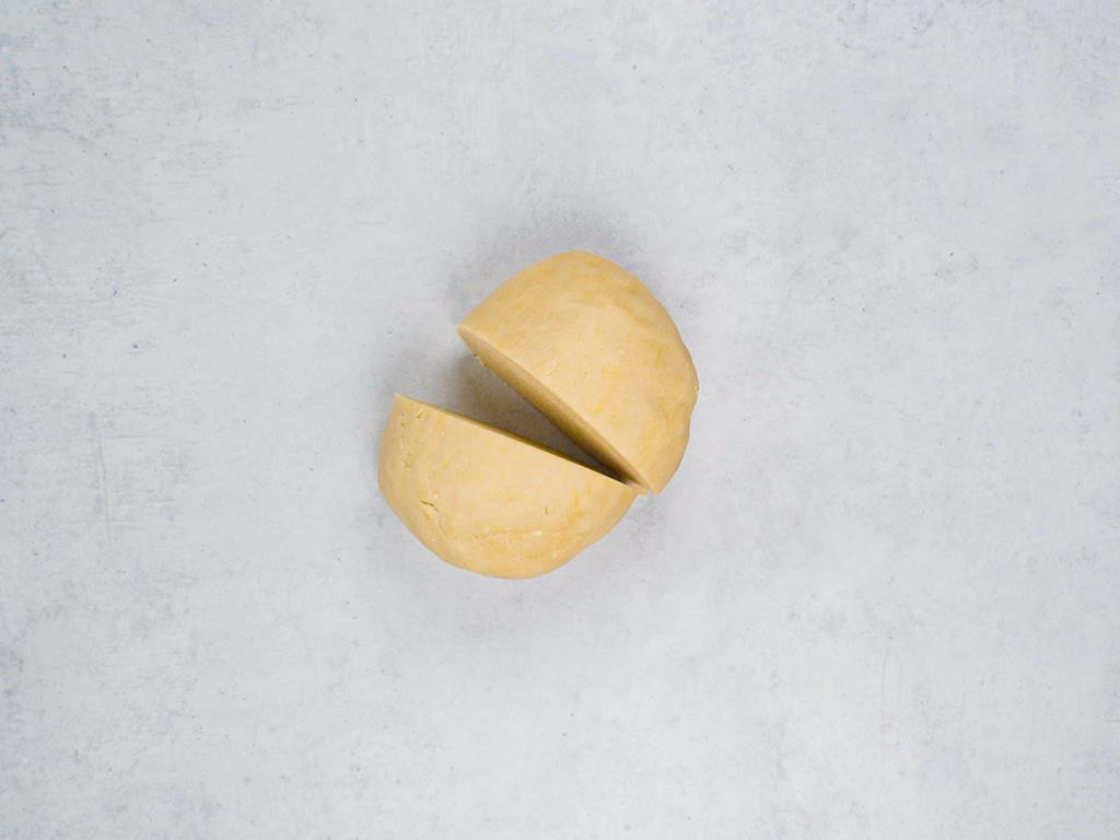 Zagniecione ciasto uformowane w kulę i przekrojone na pół