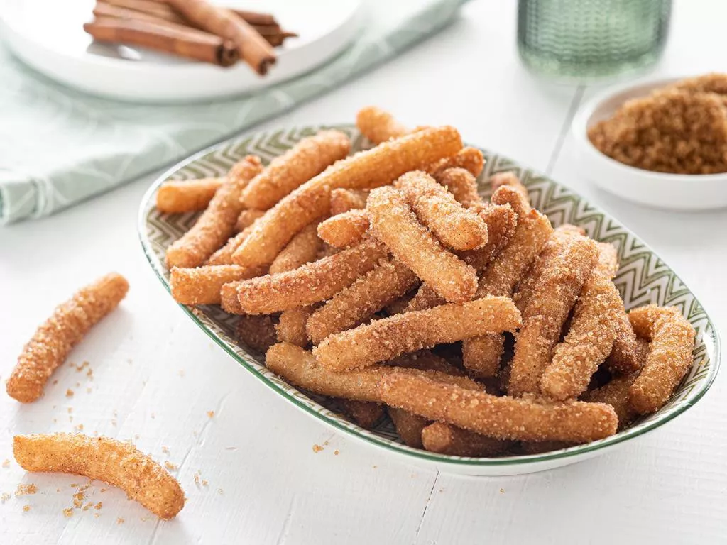 wegańskie churros w cynamonowej posypce na zielonym podłużnym talerzyku