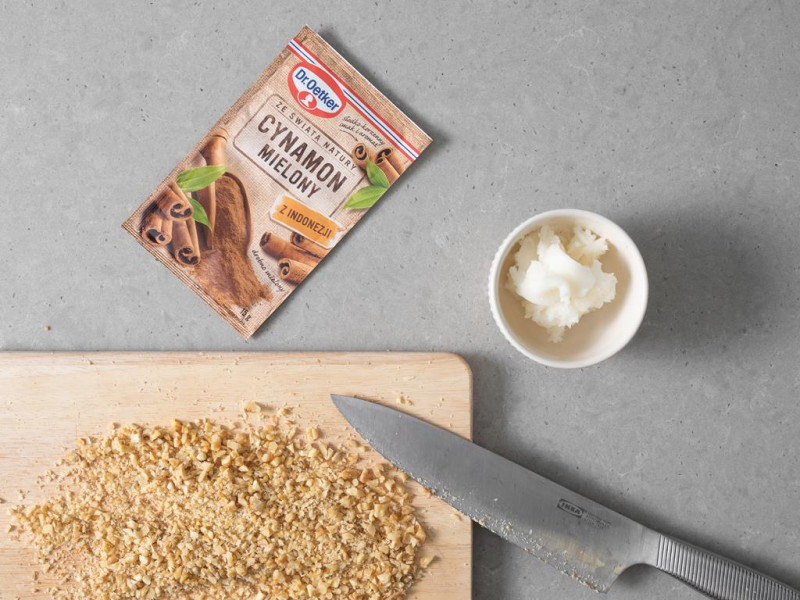 Posiekane orzechy włoskie na drewnianej desce. Obok cynamonowe nadzienie.