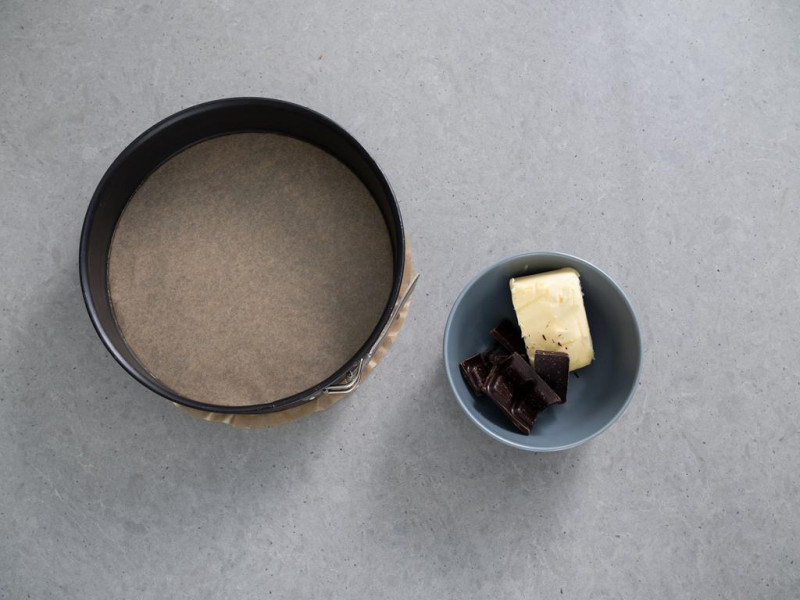 na stole tortownica 24 cm dr. oetker obok miseczka z masłem i czekoladą