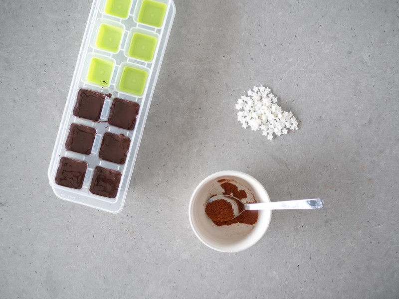 Przełożona masa czekoladowa do foremek. Obok w miseczce sproszkowane chili i cukrowe gwiazdki.