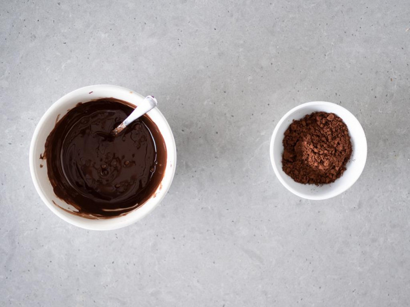 Rozpuszczona czekolada gorzka z mleczną w miseczce. Obok kakao ciemne Dr. Oetker.