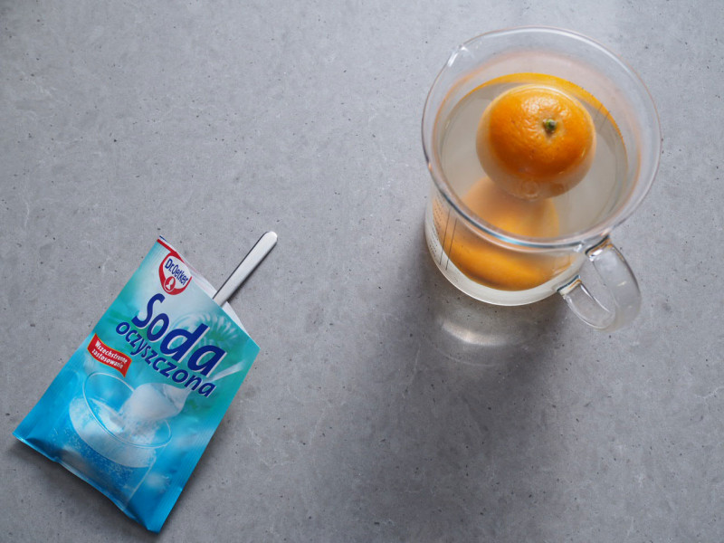 na blacie otwarte opakowanie sody dr. oetkera z łyżeczką w środku oraz wysokie szklane naczynie z zalaną wrzątkiem pomarańczą