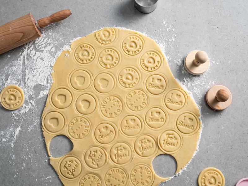 na blacie rozwałkowane ciasto z wyciśniętymi ciasteczkami