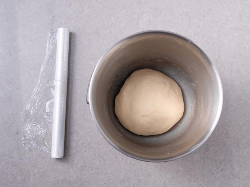 Wyrobione ciasto w misie. Obok folia spożywcza.