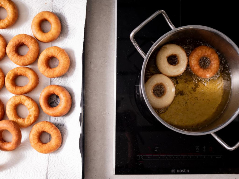 Usmażone oponki na ręczniku papierowym. Obok oponki smażone w głębokim tłuszczu,