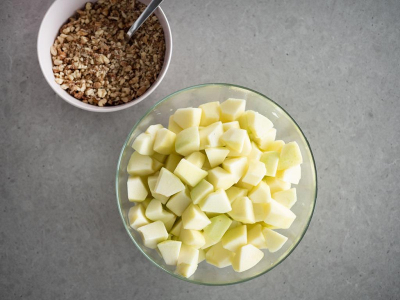 w misce pokrojone w kostkę jabłka, miseczka z orzechami włoskimi