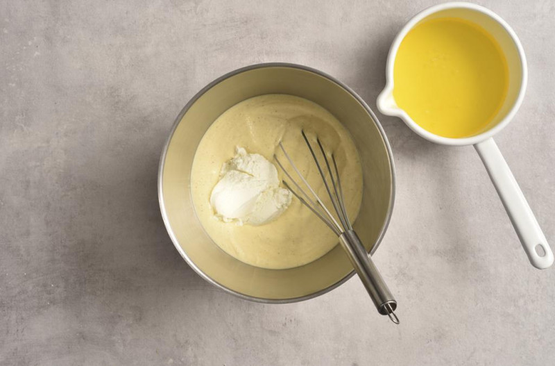 Masa serowa w misie. Obok rozpuszczone masło.