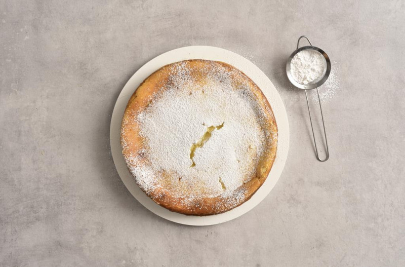 Upieczony sernik oprószony cukrem pudrem.