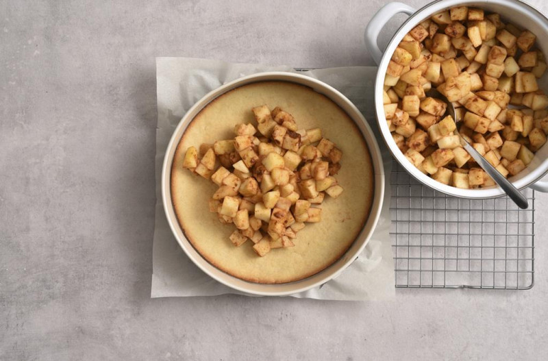 Podprażone jabłka wyłożone na spód ciasta.