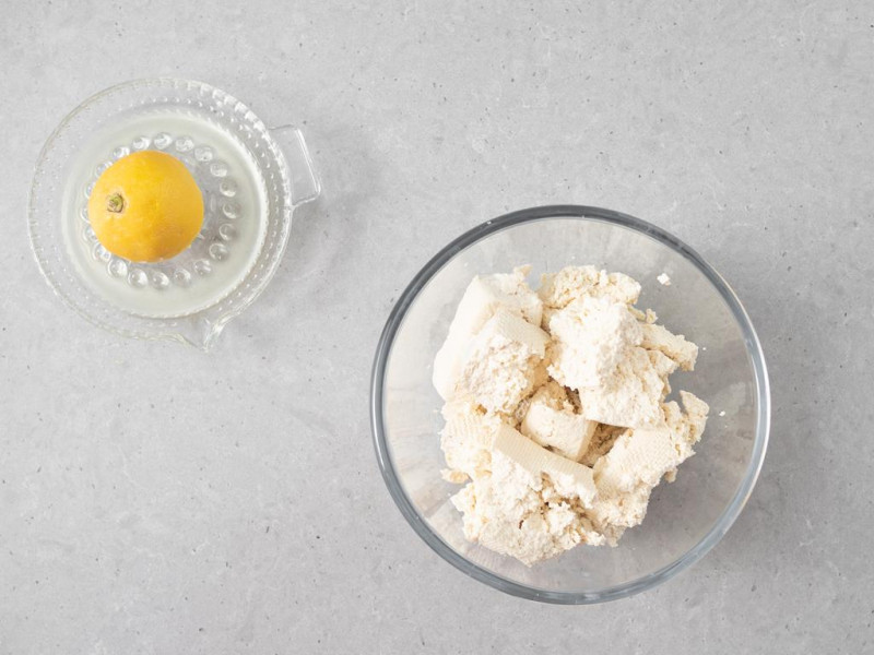 Rozkruszone tofu w misce. Obok cytryna.