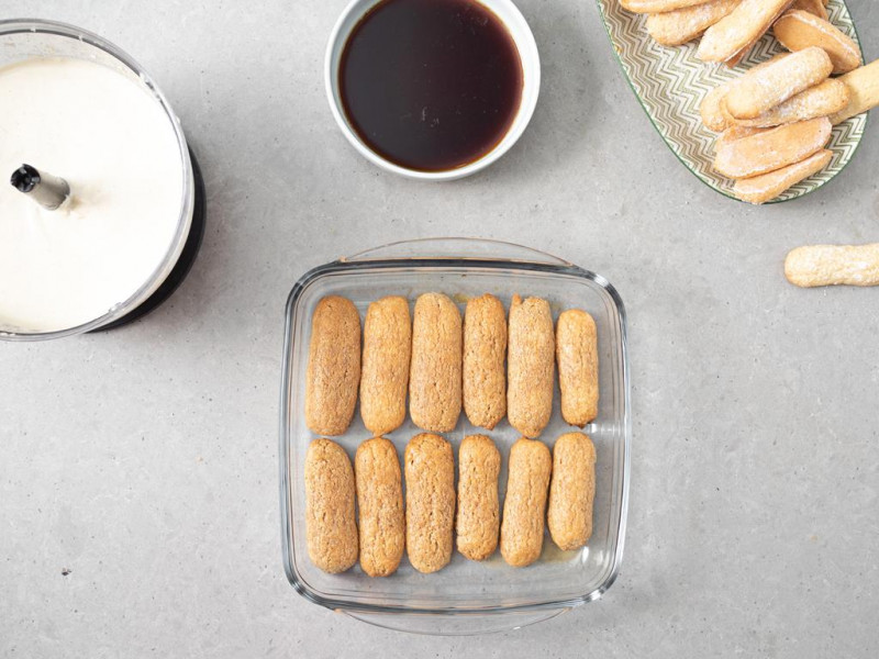 Namoczone biszkopty w kawie i amaretto, ułożone na dnie naczynia.