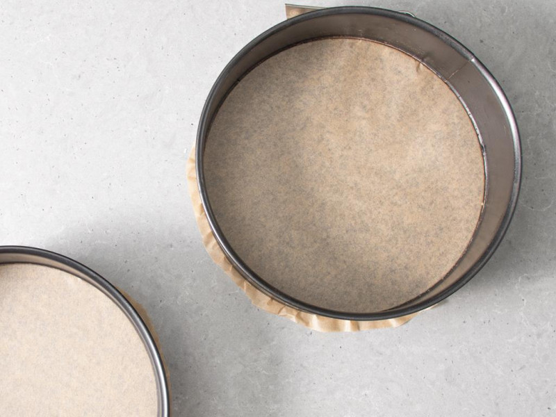 Dwie formy Dr. Oetkera o średnicy 24 cm wyłożone papierem do pieczenia.