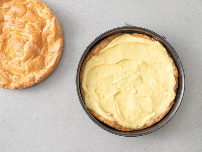 Na jednym blacie ciasta parzonego rozłożony krem budyniowy.