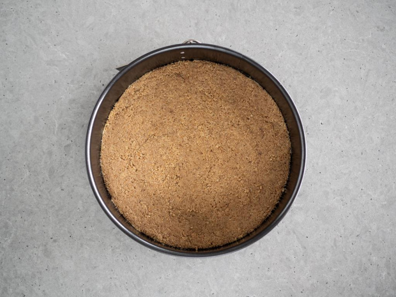 pokruszone herbatniki z masłem, cynamonem na dnie tortownicy