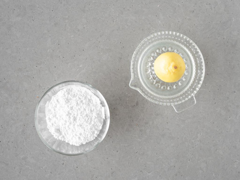 Cukier puder w miseczce oraz sok z cytryny.
