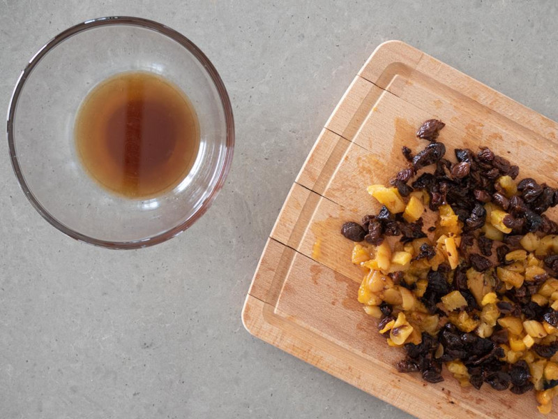 Posiekane bakalie na drewnianej desce. Obok płyn po odsączeniu bakalii.