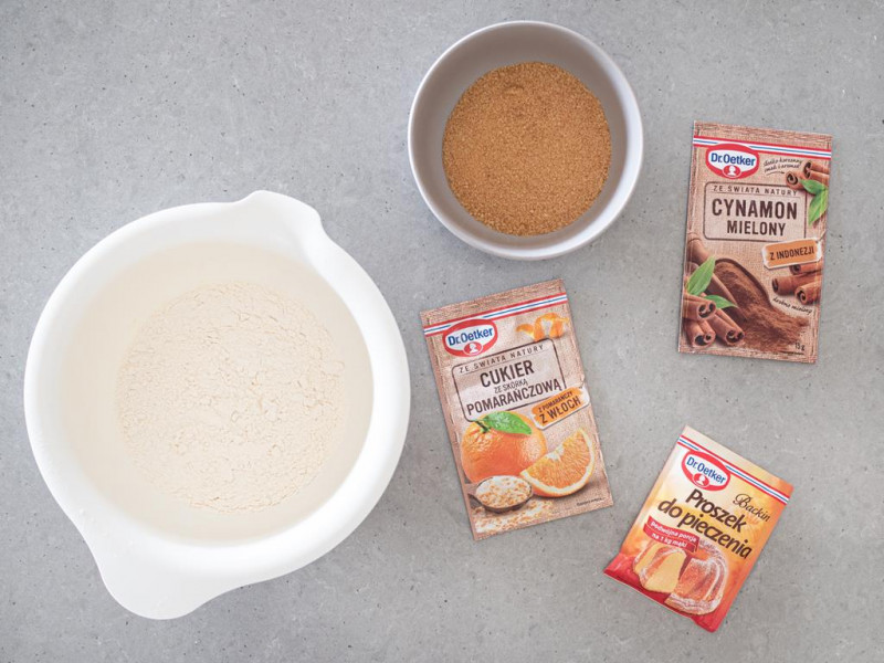 Mąka pszenna w misie. Obok cukier trzcinowy, cynamon mielony Dr. Oetkera, cukier ze skórką pomarańczową Dr. Oetker i proszek do pieczenia Dr. Oetkera