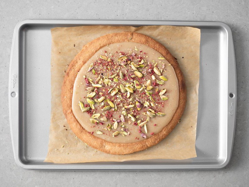 Wegański mazurek kajmakowy udekorowany pistacjami i liofilizowanymi owocami.