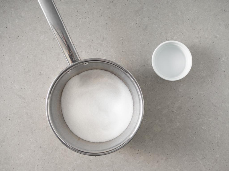 W garnku cukier. Obok w miseczce woda.