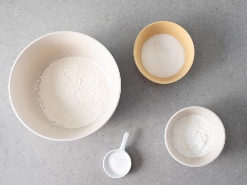 W misce mąka pszenna, obok mąka ziemniaczana, cukier i proszek do pieczenia Dr. Oetkera.