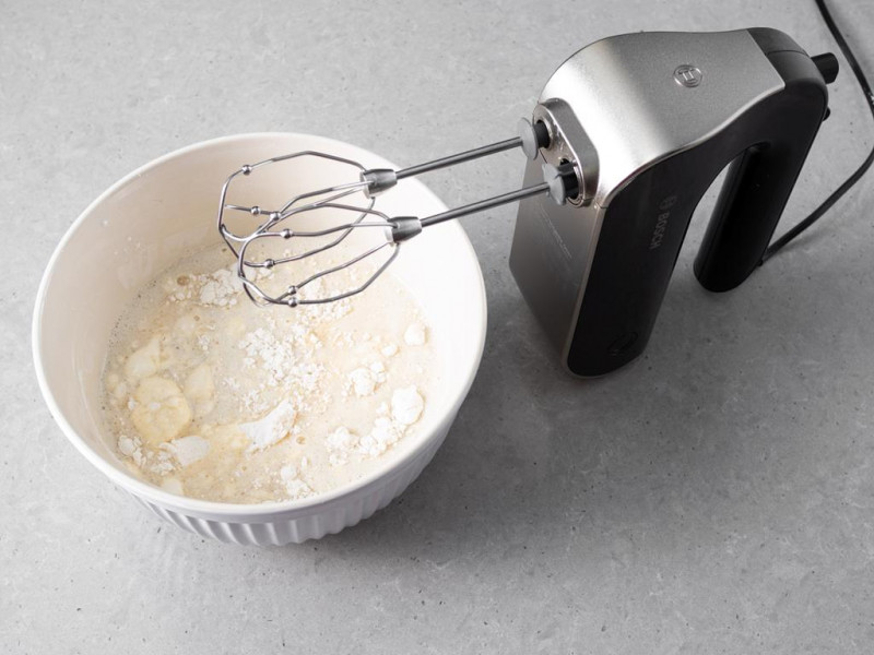 Ciasto na biszkopty przed zagnieceniem w misie ceramicznej, obok mikser ręczny firmy Bosch.