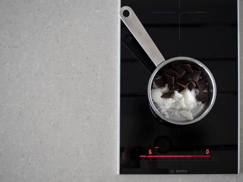 Gorzka czekolada w garnku z olejem kokosowym na płycie 2-palnikowej firmy Bosch.