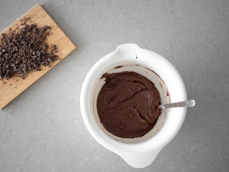 Gotowa czekoladowa masa na ciasteczka. Obok kawałki czekolady na desce.