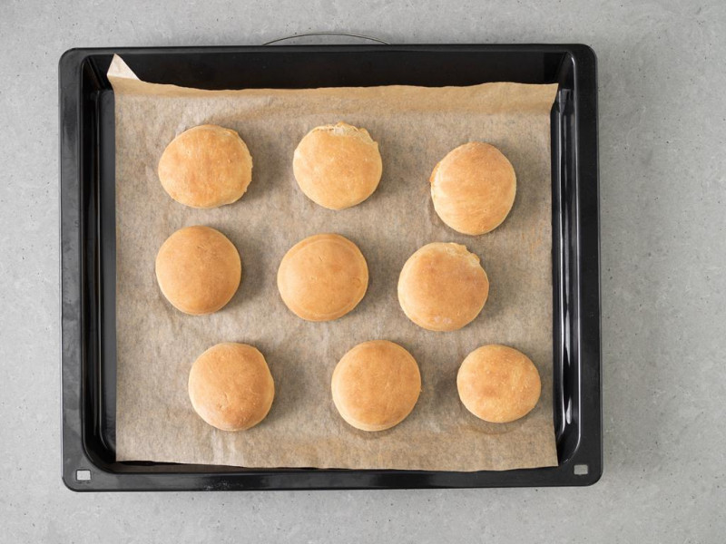 Upieczone wegańskie pączki na blasze do pieczenia.