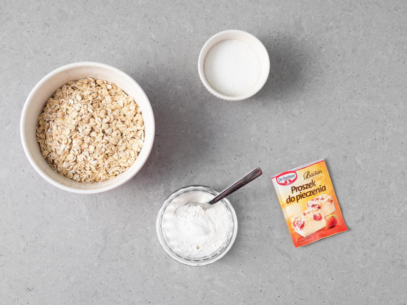 W misie płatki owsiane. Obok proszek do pieczenia Dr. Oetkera, cukier i mąka pszenna.