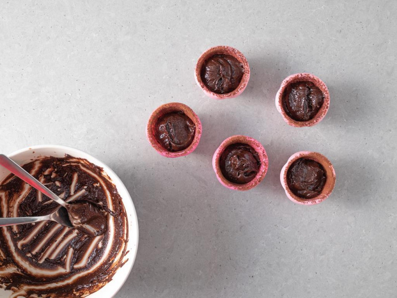 Foremki wypełnione ciastem czekoladowym.