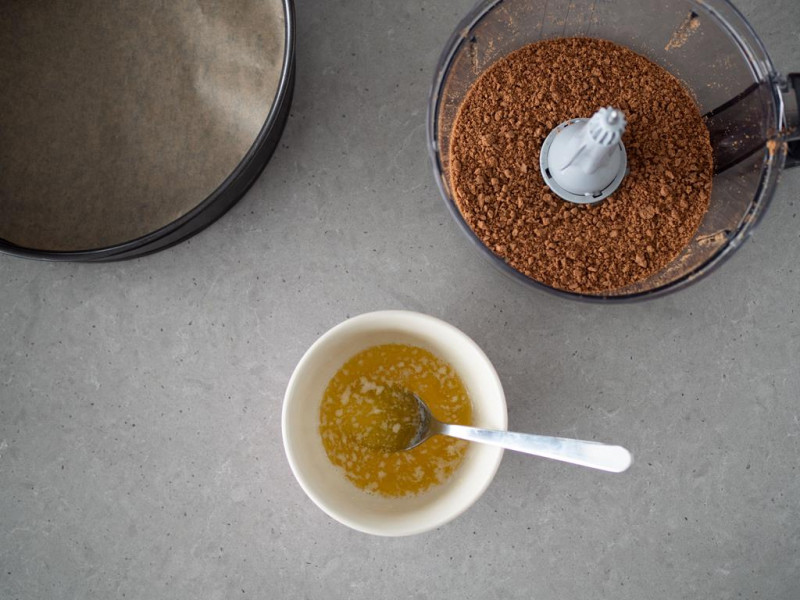 w miseczce roztopione masło obok malakser bosch z pokruszonymi kakaowymi ciasteczkami