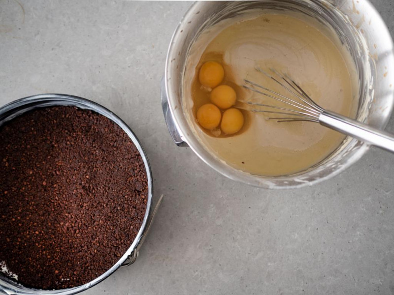 tortownica z wyłożonym spodem, obok misa z masa na sernik kawowy