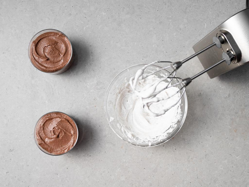 Czekoladowy mus z tofu w szklankach, a obok ubita śmietanka kokosowa.