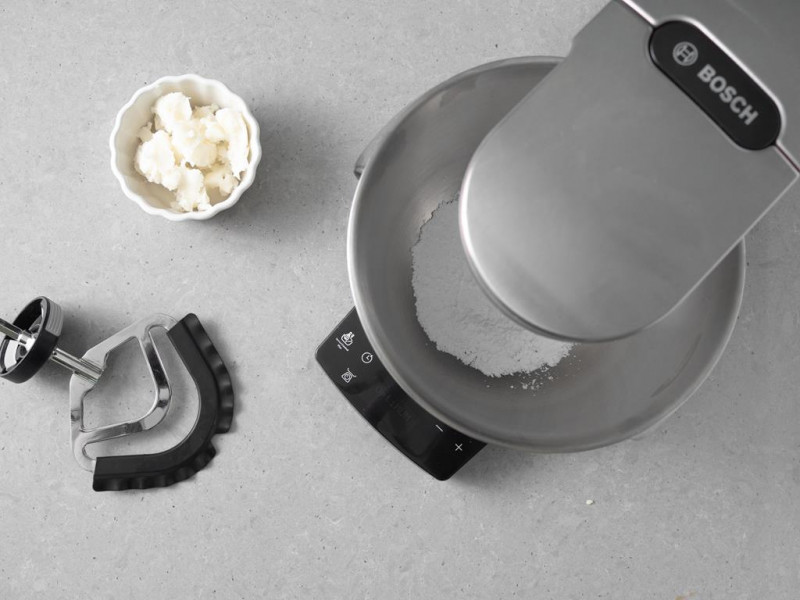 Robot kuchenny firmy Bosch, a w misie cukier puder. Obok olej kokosowy w miseczce.