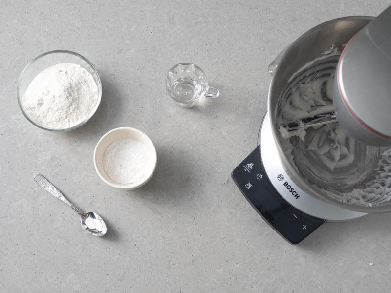 W misie miksera utarty cukier puder z olejem kokosowym. Obok sól na łyżeczce, mąka pszenna i ziemniaczana w miseczkach i zimna woda.