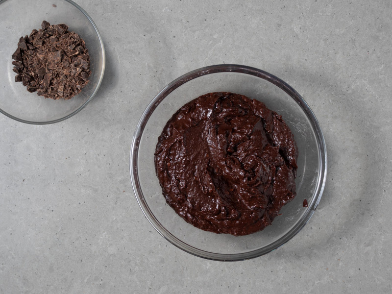 W dużej misie masa na ciasto czekoladowe z fasoli. Obok kawałki posiekanej czekolady.