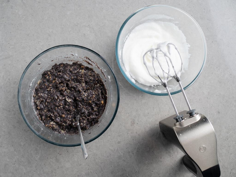 masa makowa z bakaliami w misce i ubite białka w drugiej misce z mikserem