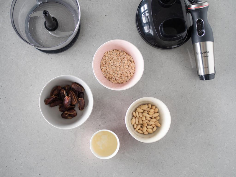 Daktyle, migdały, płatki owsiane i olej kokosowy w osobnych miseczkach