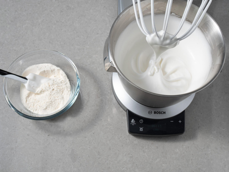 W misie robota kuchennego białka ubite z cukrem. Obok w miseczce mąka wymieszana z pozostałym cukrem.
