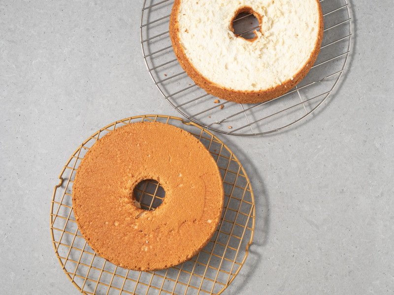 Ciasto anielskie przekrojone na dwa blaty i ułożone na kratkach do studzenia.