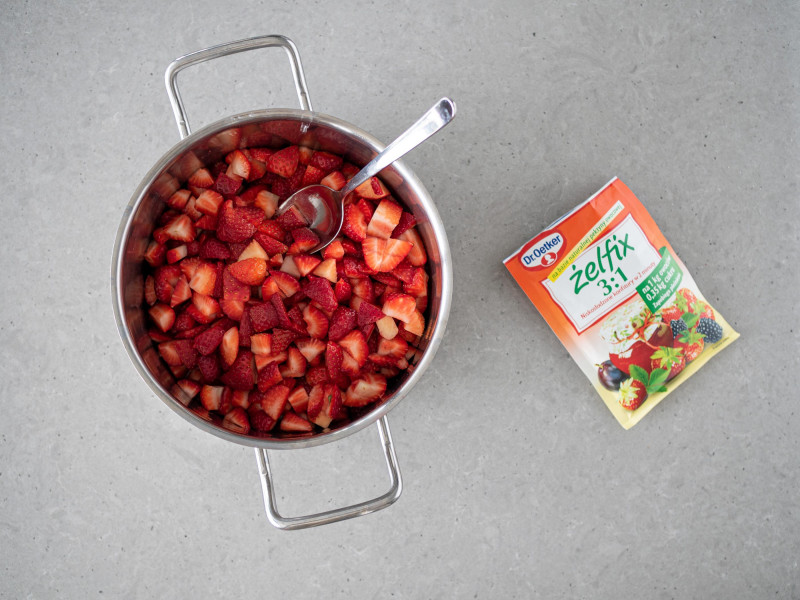W garnku pokrojone truskawki. Obok żelfix 3:1 Dr. Oetkera.