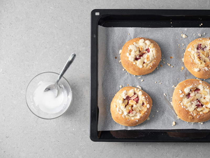 Lukier w miseczce. Obok upieczone drożdżówki.