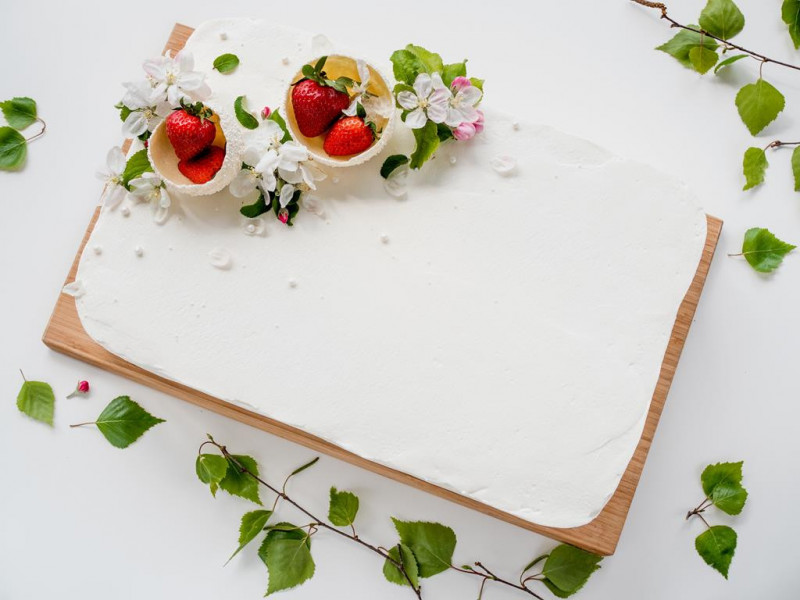 Tort truskawkowo-kokosowy udekorowany miseczkami, truskawkami i kwiatami