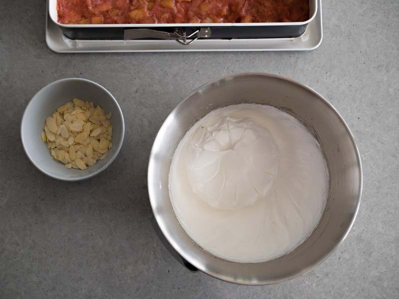 w misie robota kuchennego bosch ubita piana na bezę obok miseczka z płatkami migdałów